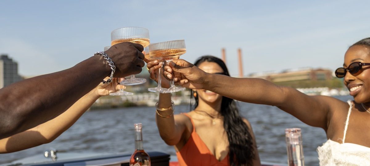 Friends toasting rosé over a charcuterie spread on a Yachtsy cruise